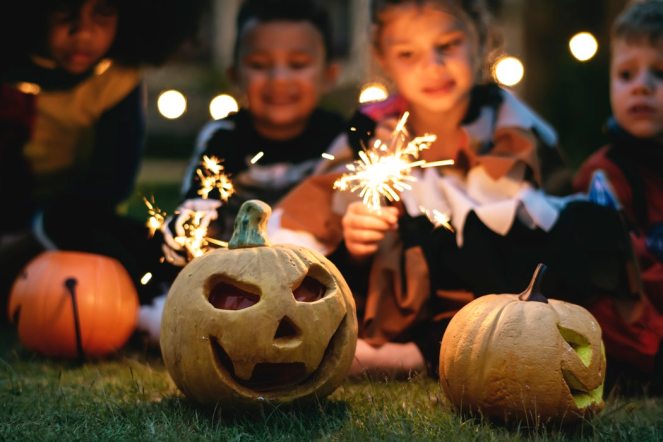 Two halloween pumpkins and children with sparklers